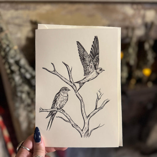 Hand holding a card with bird illustration against a blurred background