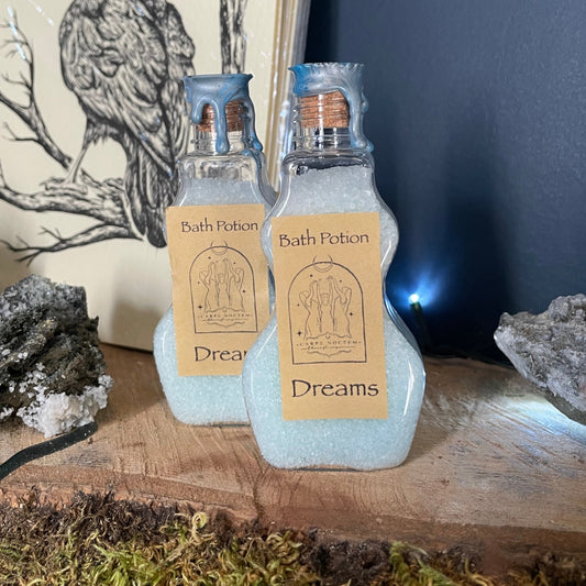 Bath & Body Works candle with 'Dreams' label on a natural setting with stone and moss.