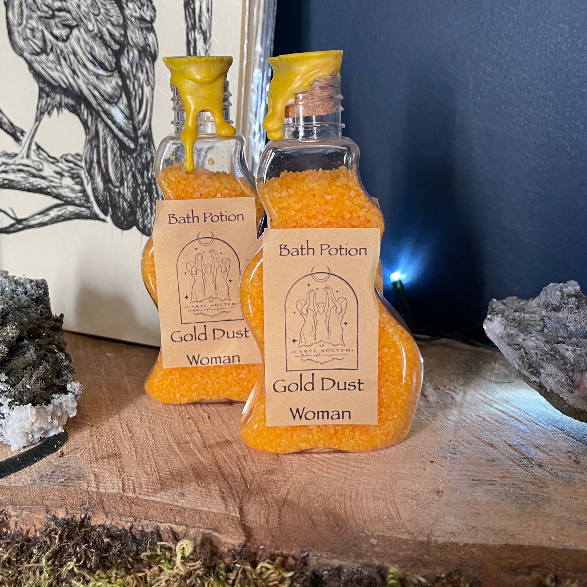 Two bottles of Gold Dust Women's body wash on a wooden surface with nature-themed background