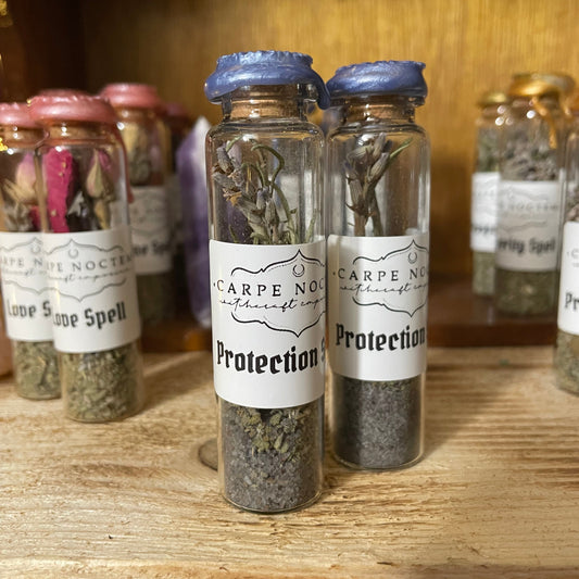 Collection of small glass jars with labels on a wooden surface