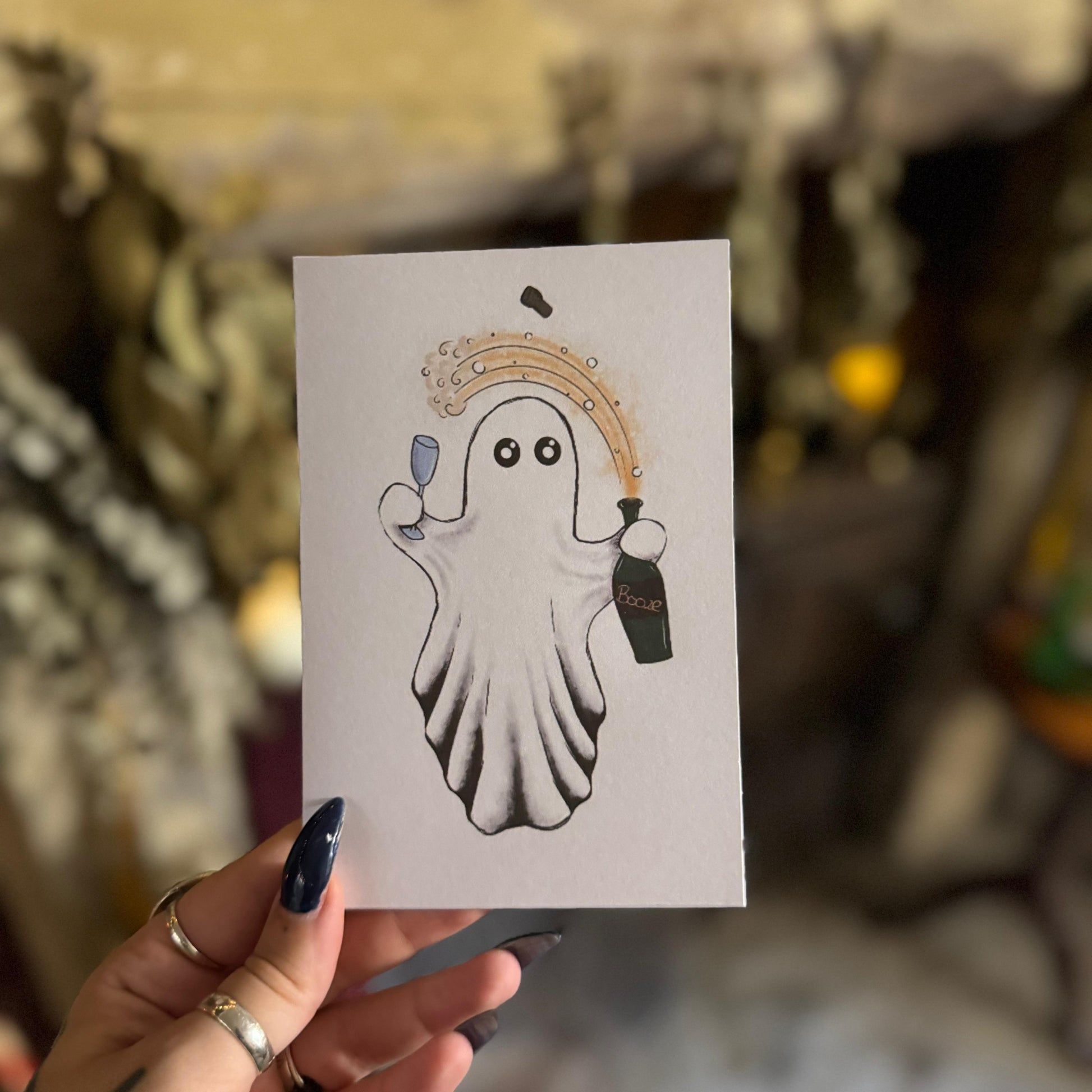 Hand holding a card with a ghost illustration against a blurred background