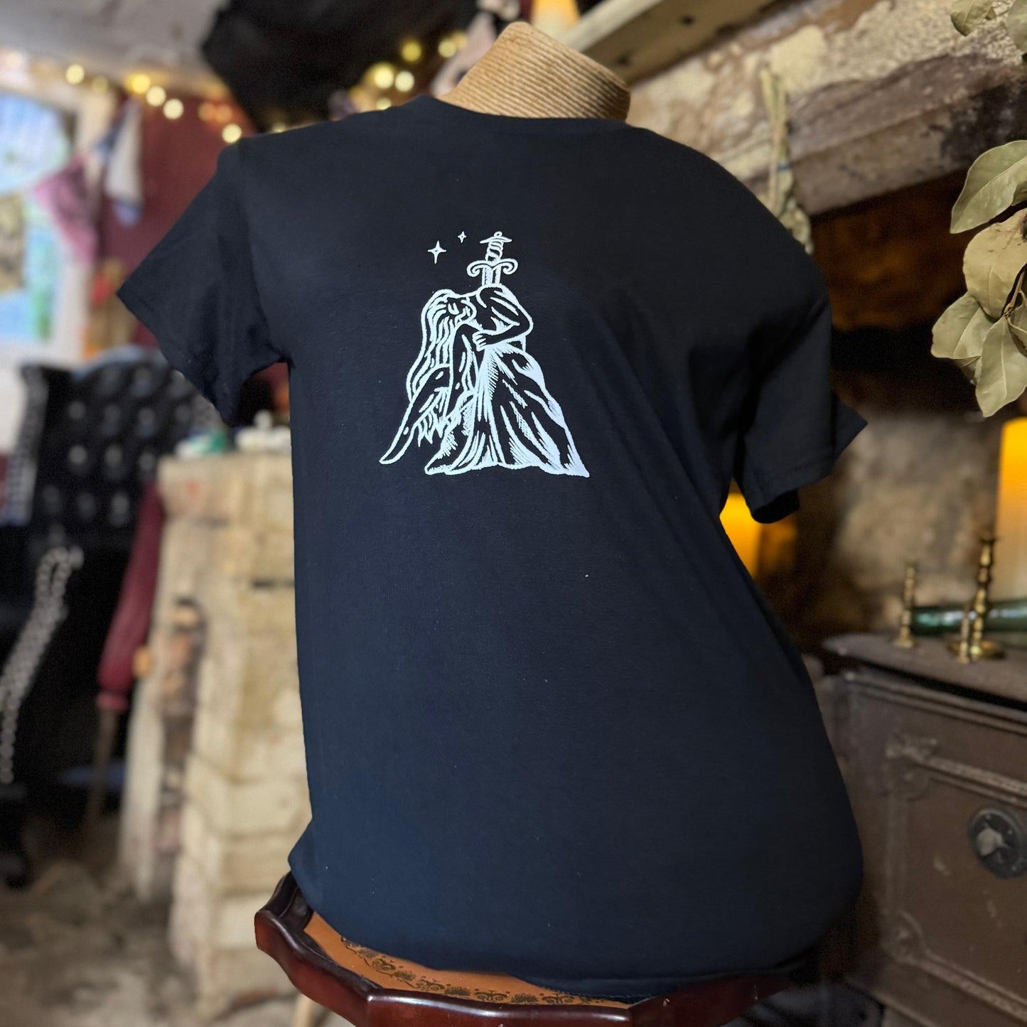 Black t-shirt with a white graphic design on the back, worn by a person in a store setting.