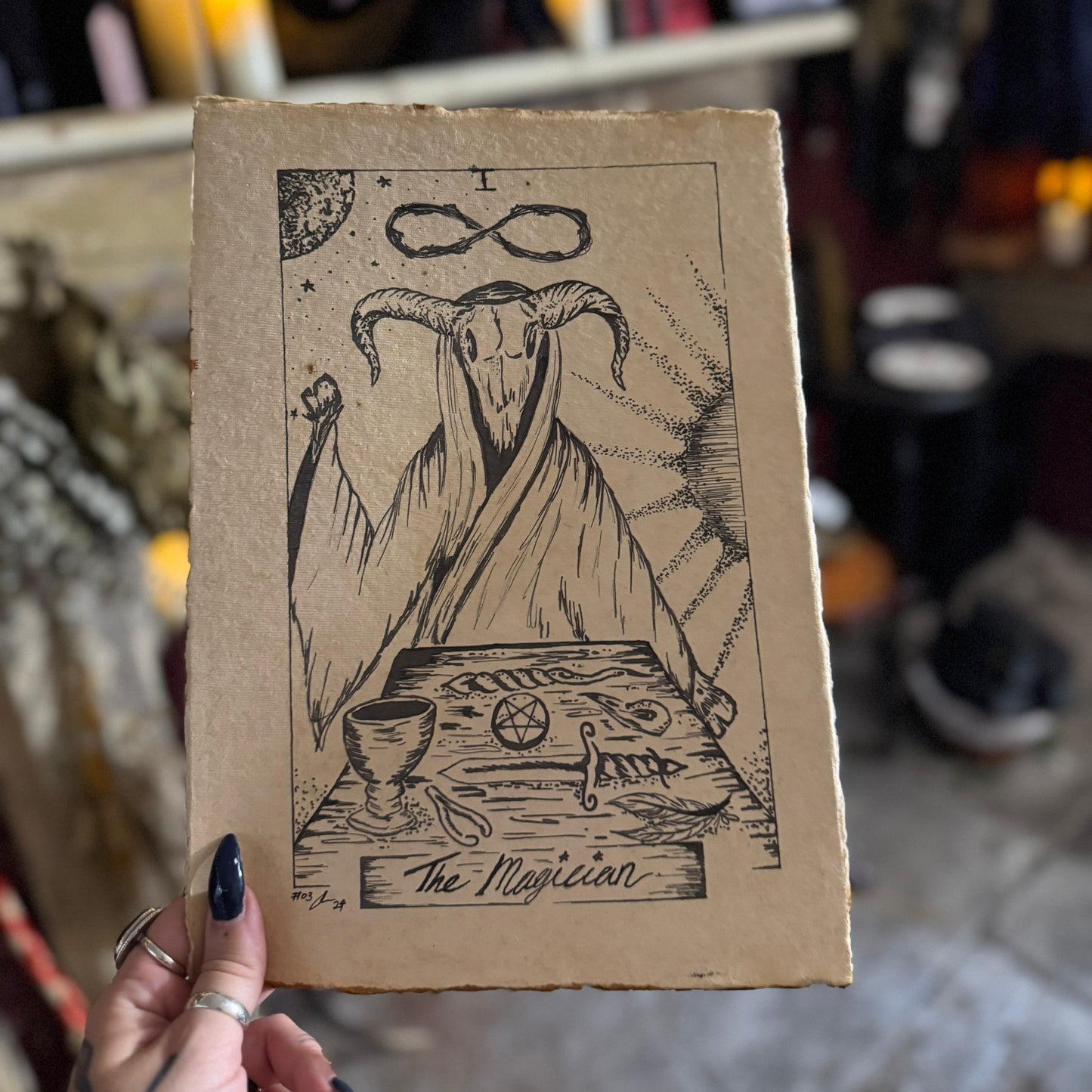 Card with 'The Magician' illustration held in front of a blurred indoor background